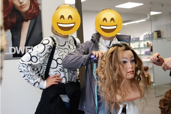 Zwei Schülerinnen frisieren bei Hallo Zukunft im Wegmeyer Haarstudio einen Übungskopf und lernen erste Handgriffe des Friseurberufs