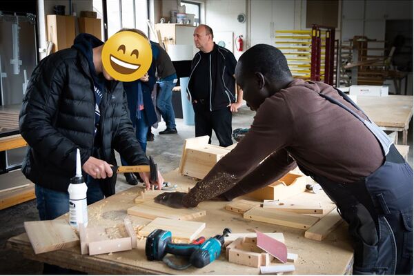 Mitarbeiter der Tischlerei Heuer unterstützt einen Schüler beim Bau eines Vogelhäuschens während des Projekts Hallo Zukunft