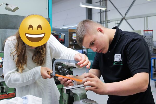 Ein Auszubildender der hankensbütteler kunststoffverarbeitung hilft einer Schülerin beim Feilen eines Flaschenöffners während des Projekts Hallo Zukunft